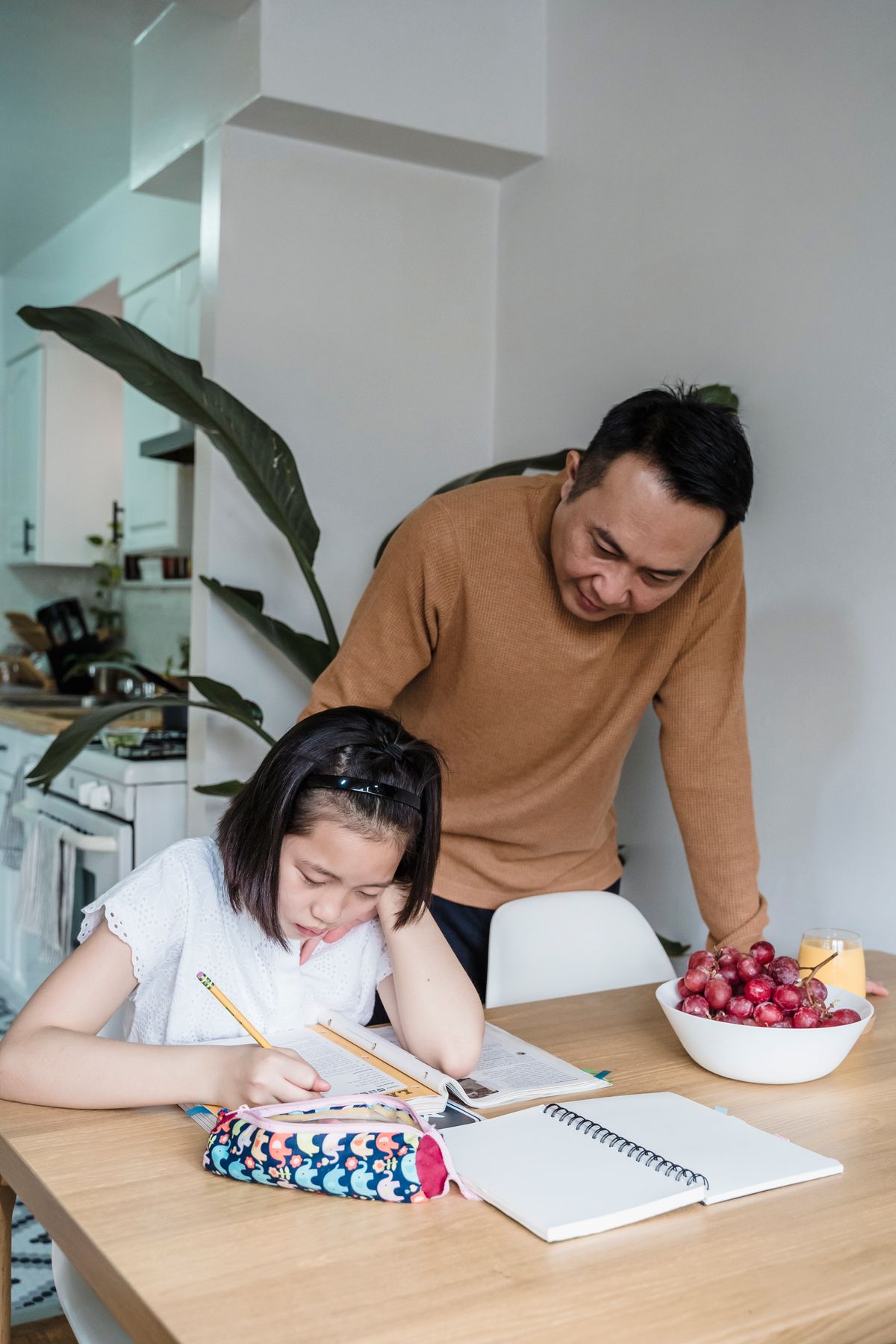 A Father Looking at His Daughter While Doing Homework